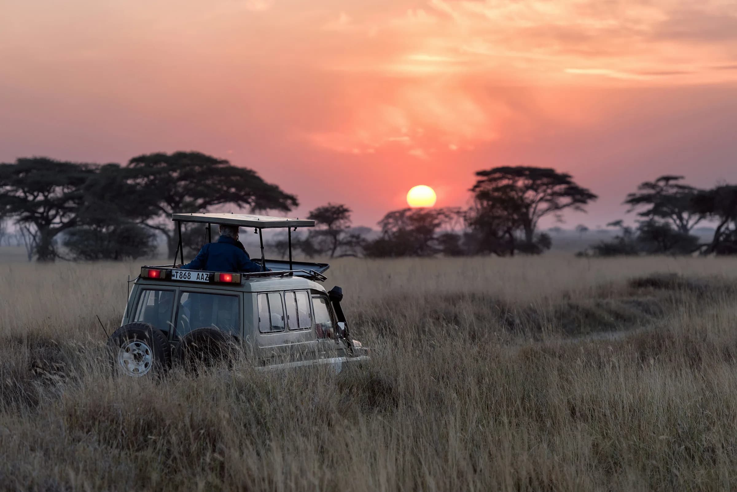 Safari vehicle at sunset on the Serengeti plains, Tanzania