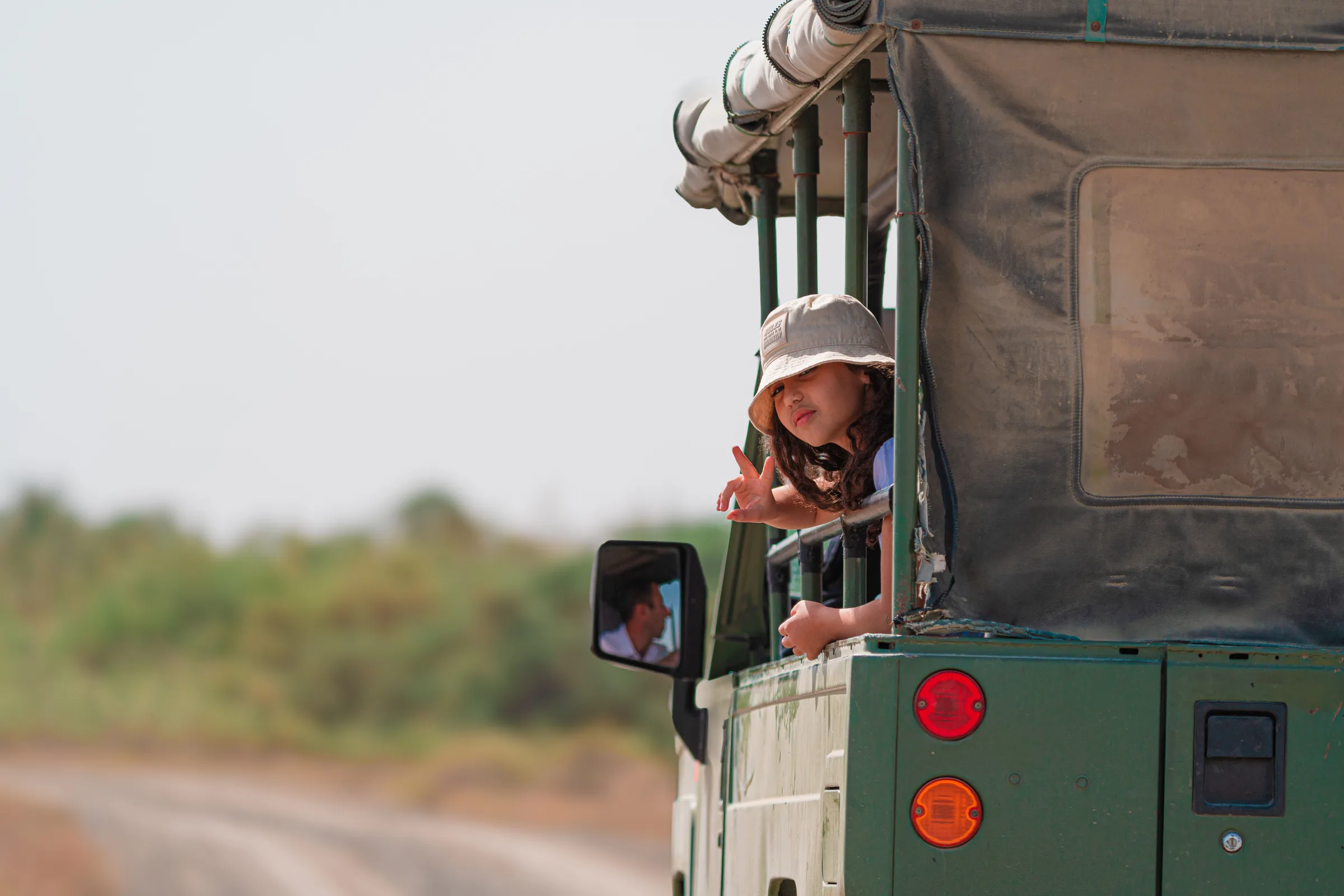 Child watching wildlife from an open-top safari vehicle